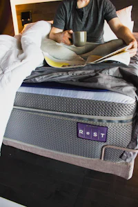 a man reading a book on top of a mattress