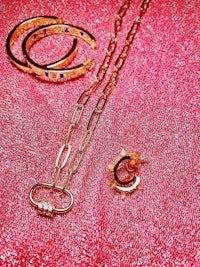 a set of gold jewelry on a pink background
