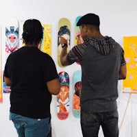 two men looking at skateboards on a wall