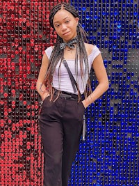 a woman with dreadlocks standing in front of a wall