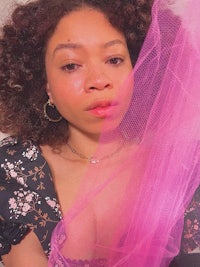 a woman with a curly afro is holding a pink tulle